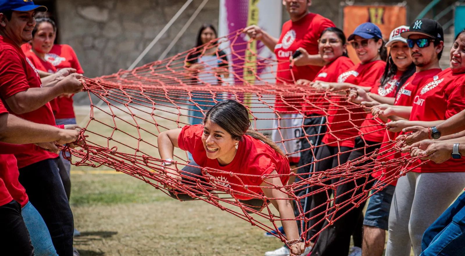 Un grupo sostiene una red mientras una participante la atraviesa en un juego de equipo