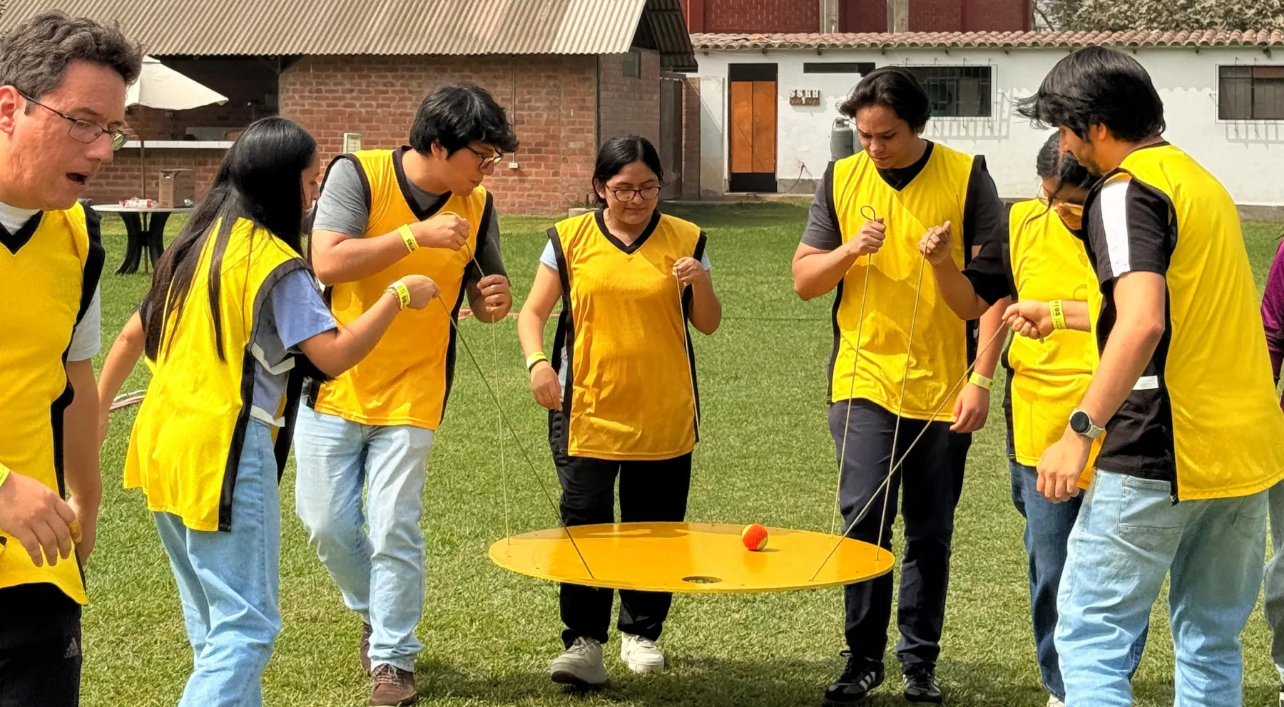 Un equipo con petos amarillos mueve una pelota sobre un disco sujeto con cuerdas