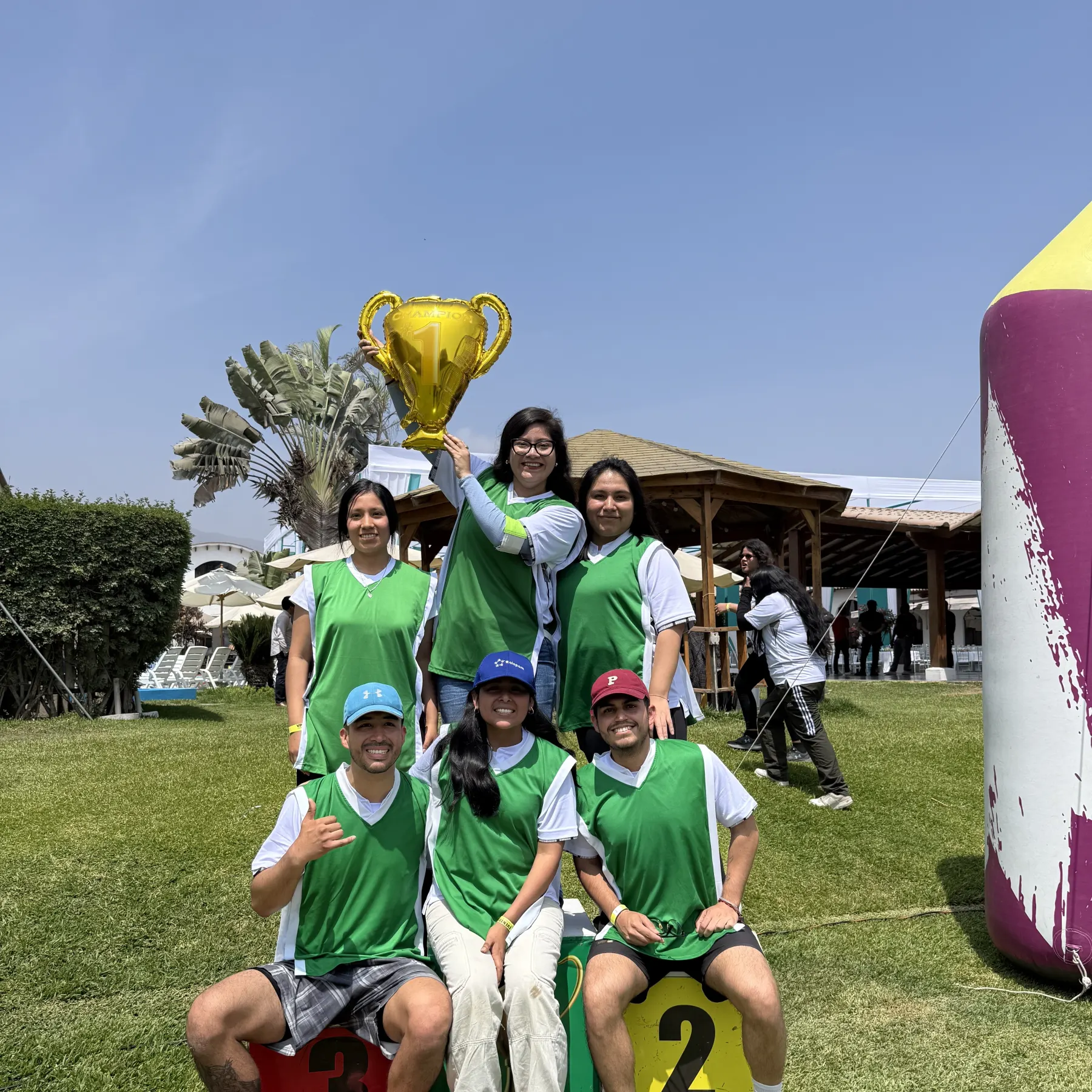 Un equipo con petos verdes levanta el trofeo tras ganar una competencia al aire libre
