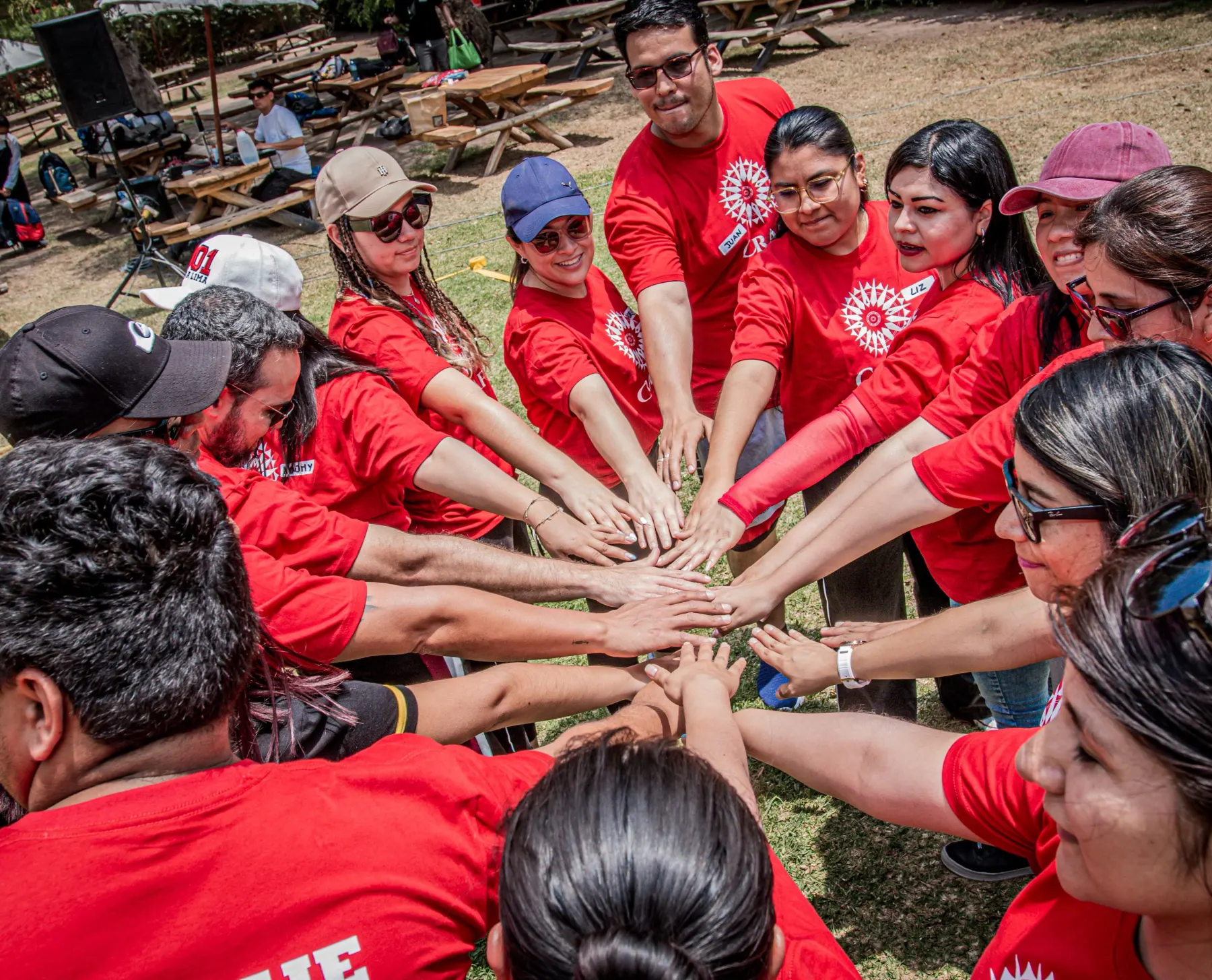 Un equipo con polos rojos junta las manos en el centro de un círculo antes de empezar una dinámica